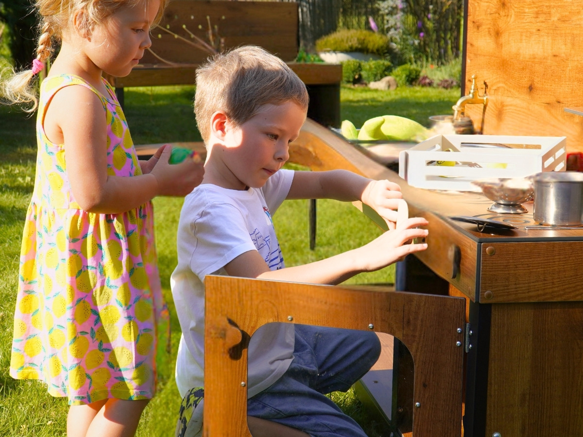 A boy putting a toy into the open oven with a transparent window in the door