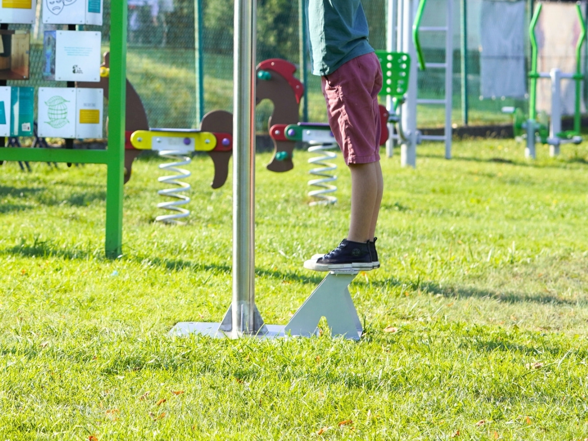 Podnóżek ustawiony przy słupku lunety, dziecko stoi na nim i&nbsp;patrzy przez okular