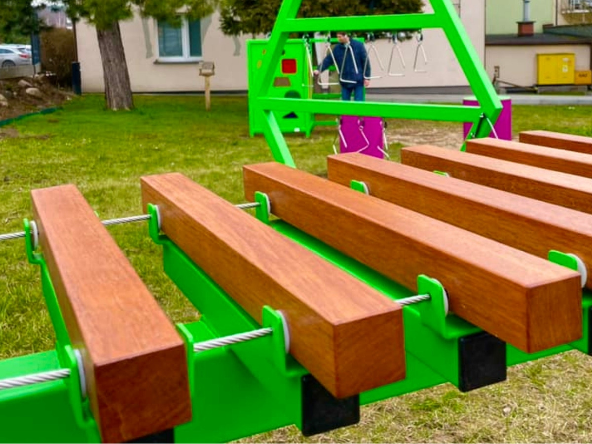 Zbliżenie na zawieszenie drewnianej płytki ksylofonu na lince ze stali nierdzewnej w&nbsp;stalowej ramie