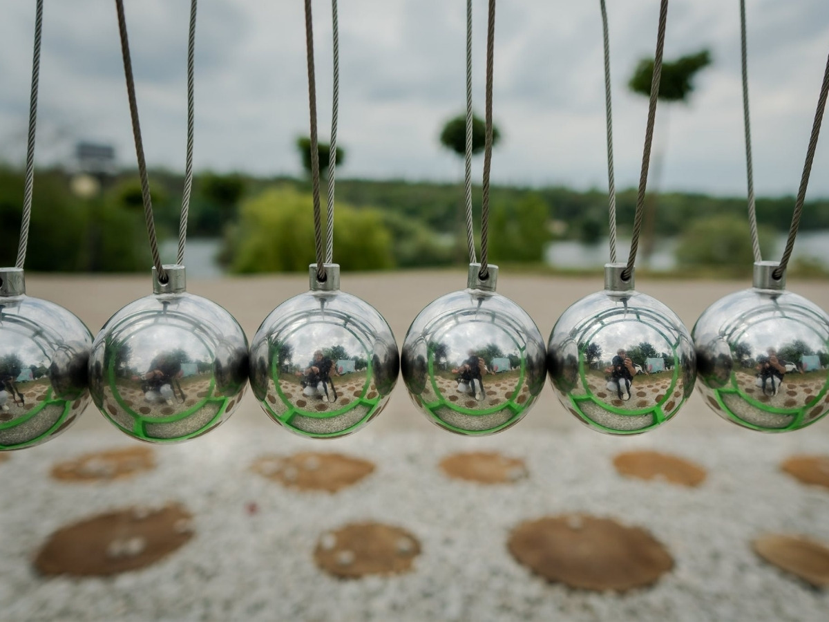 A row of steel balls hung in a single line in the frame of the Newton's cradle, the end ball pulled out to the side