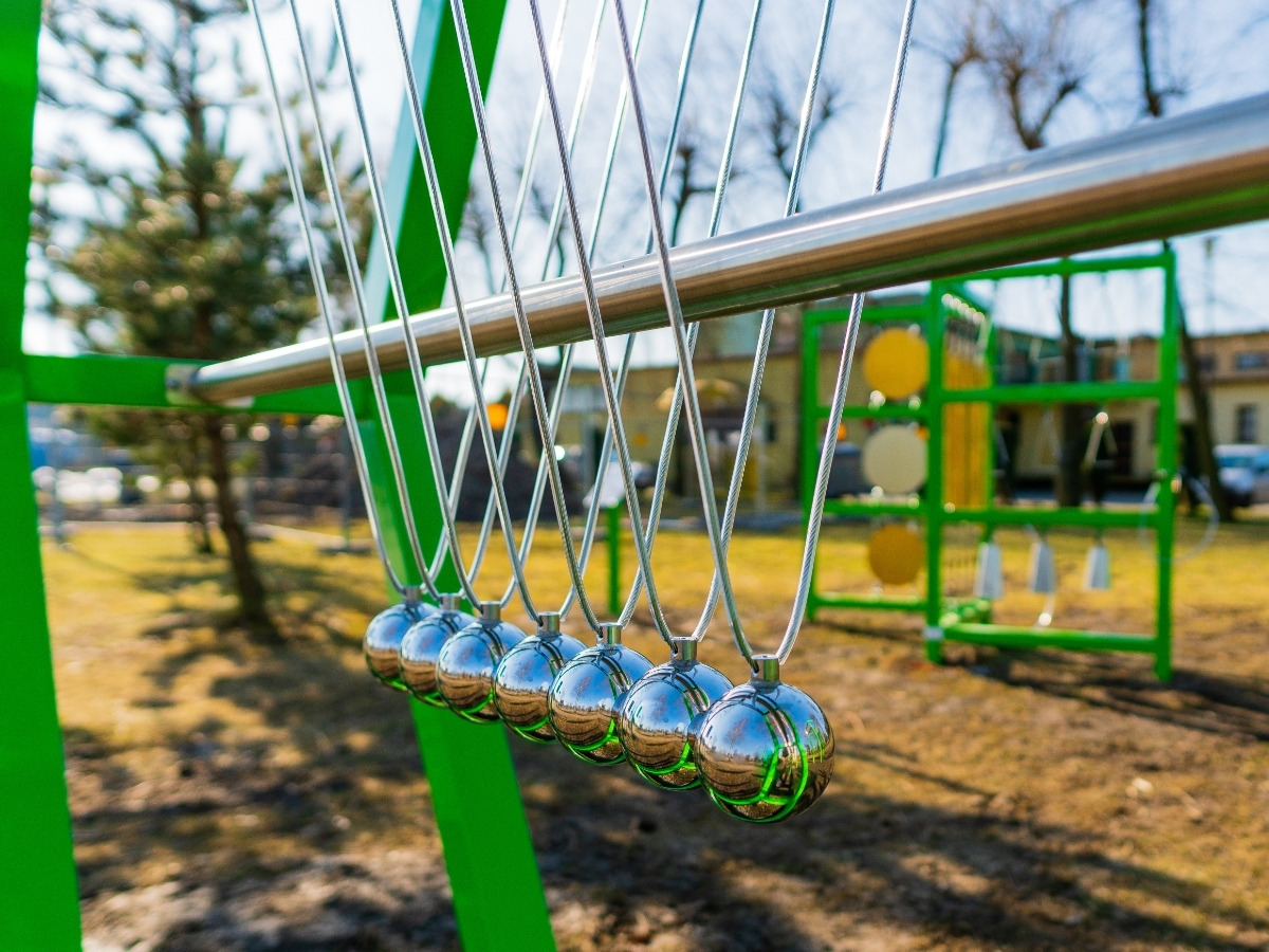 Close-up of a ball's suspension: a stainless steel cable fixed in the top beam of the Newton's cradle frame