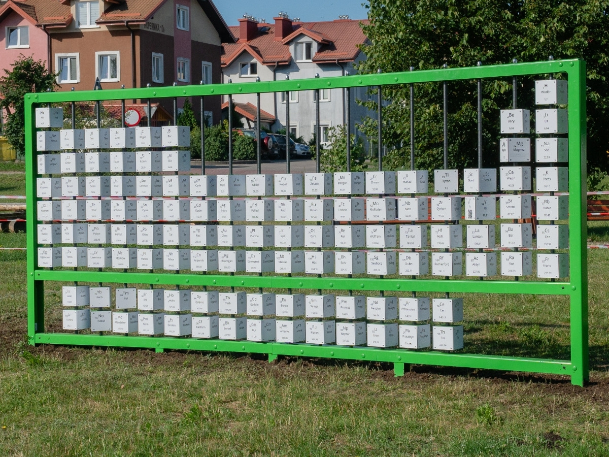 Układ okresowy pierwiastków na zielonej ramie, ustawiony na trawniku