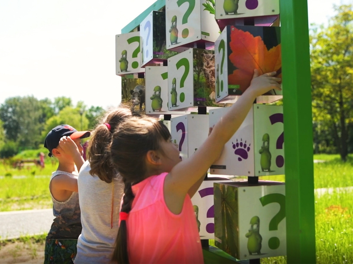 Upright memory game with rows of rotating cubes, children playing standing on both sides of the frame