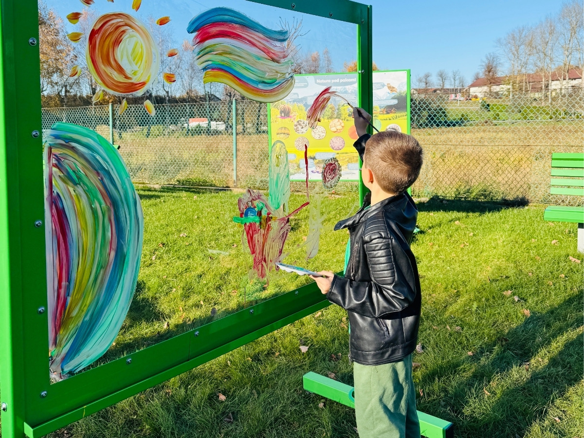 The lower part of the painting wall: the steel legs of the frame going into the grassy playground surface