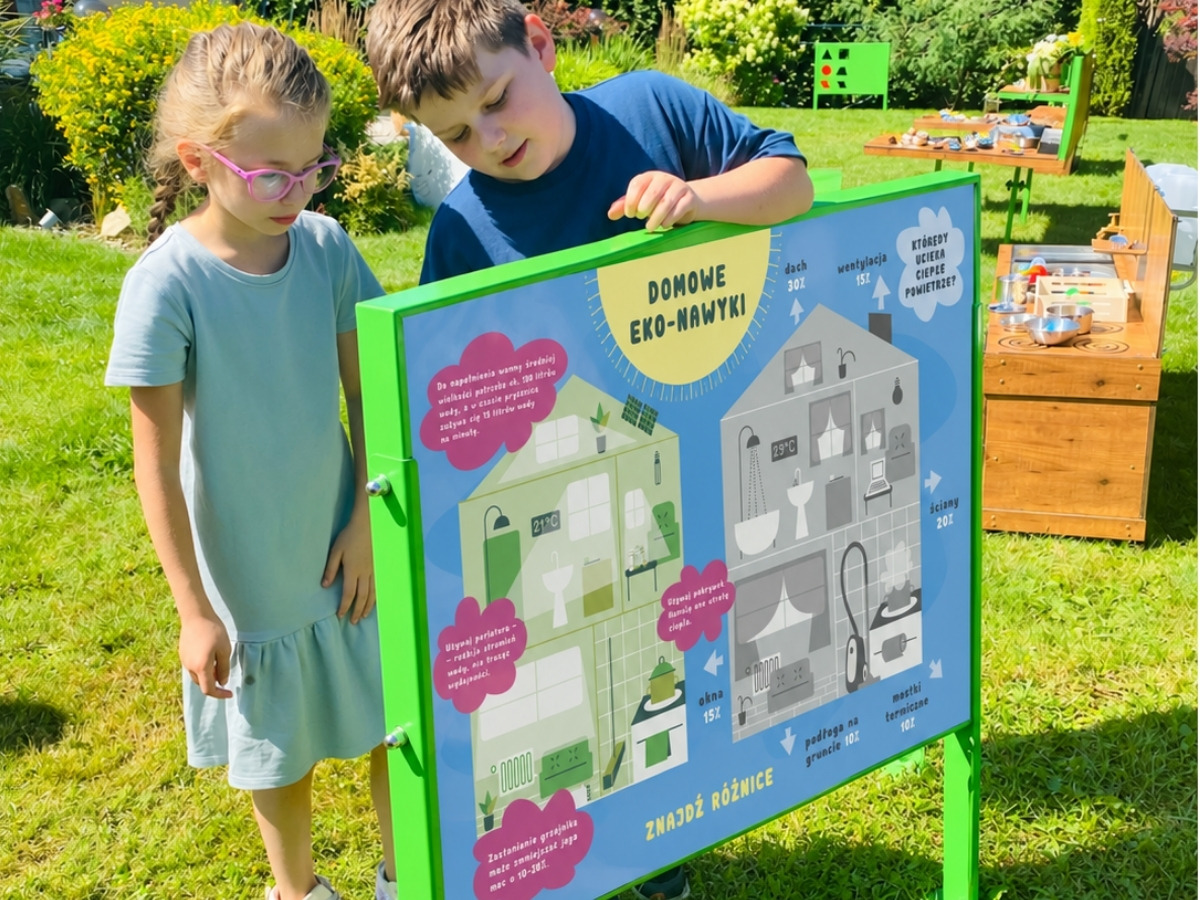 Dwustronna tablica edukacyjna w&nbsp;jednej ramie, dzieci stoją po obu stronach planszy