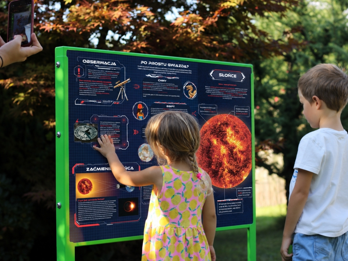 Dłoń dziecka przykłada magnetyczny element do stalowej planszy tablicy edukacyjnej