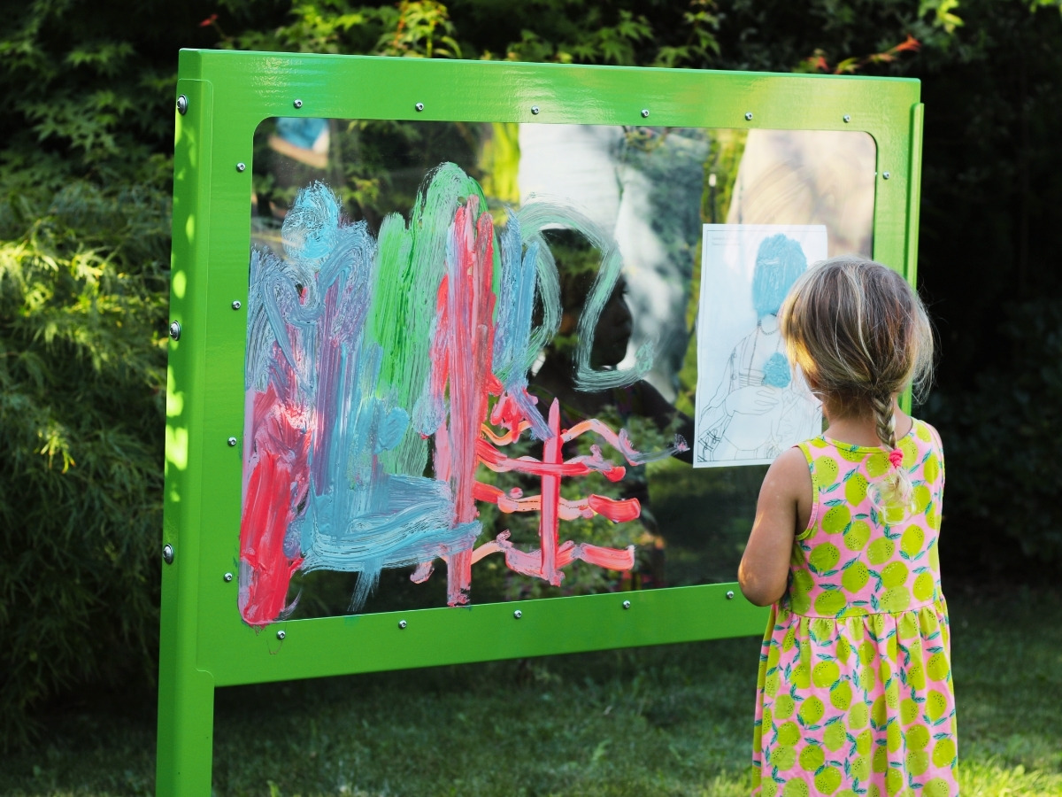 A child's hand wiping a colourful drawing off the transparent pane of the Picasso board with a damp sponge