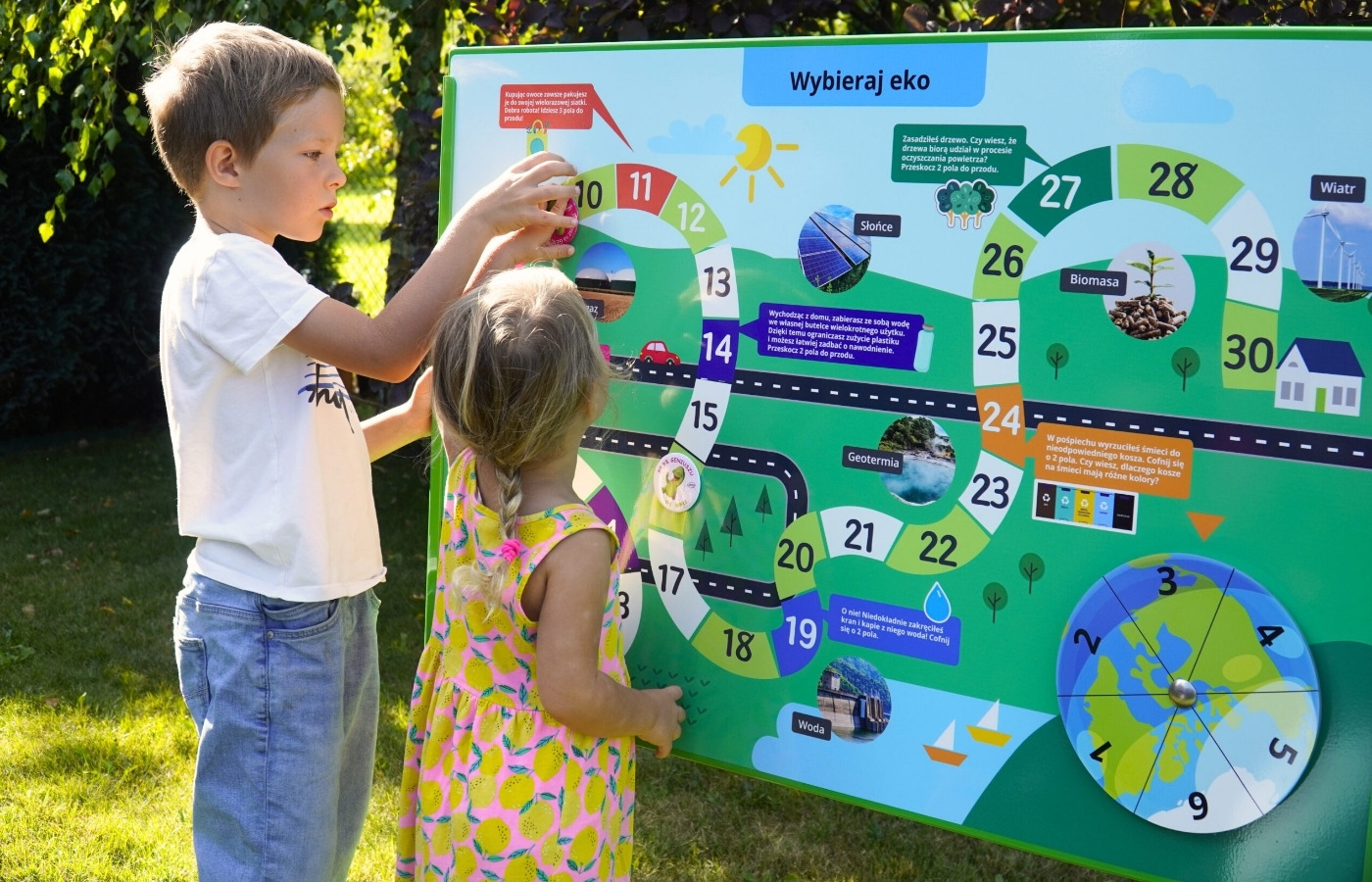Dwoje dzieci przy tablicy z&nbsp;grą planszową „Wybieraj eko”